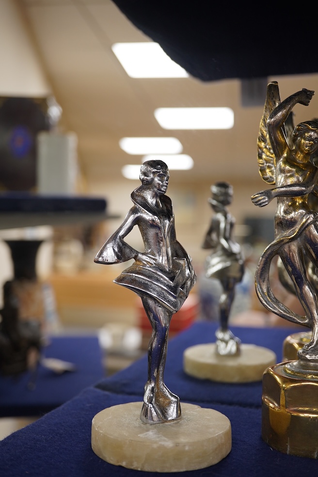 Five chrome car mascots in the form of female dancing figures, three mounted on threaded radiator caps, one with a registration number: 675619, one a stylised Art Deco winged female figure astride a globe. Condition - fa